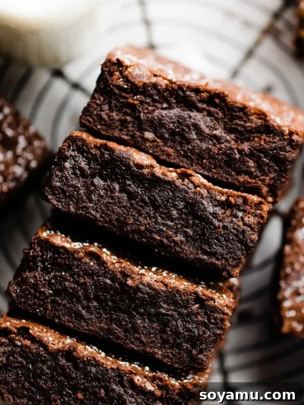 Sheet-Pan Brownies with Rich Chocolate Fudge Frosting 15 A stack of fudgy brownies with crackly tops and a dusting of powdered sugar.