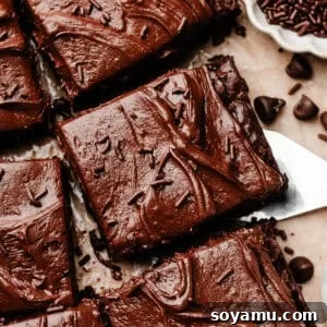 Sheet-Pan Brownies with Rich Chocolate Fudge Frosting 19 A close-up of sliced, frosted brownies with a spatula lifting one away from the rest.