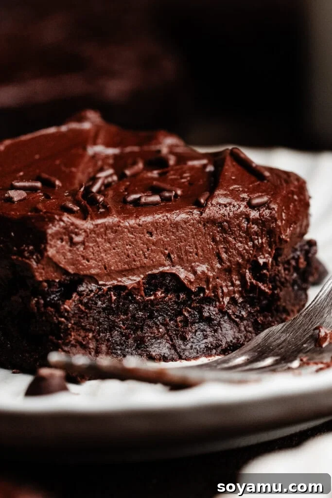 Sheet-Pan Brownies with Rich Chocolate Fudge Frosting 3 A close-up of a frosted brownie on a plate, with a bite missing.