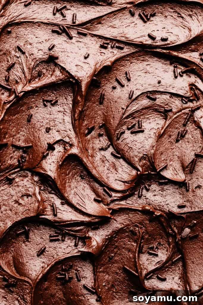 Sheet-Pan Brownies with Rich Chocolate Fudge Frosting 4 A close-up on swirls of the chocolate fudge frosting, dotted with chocolate jimmies.