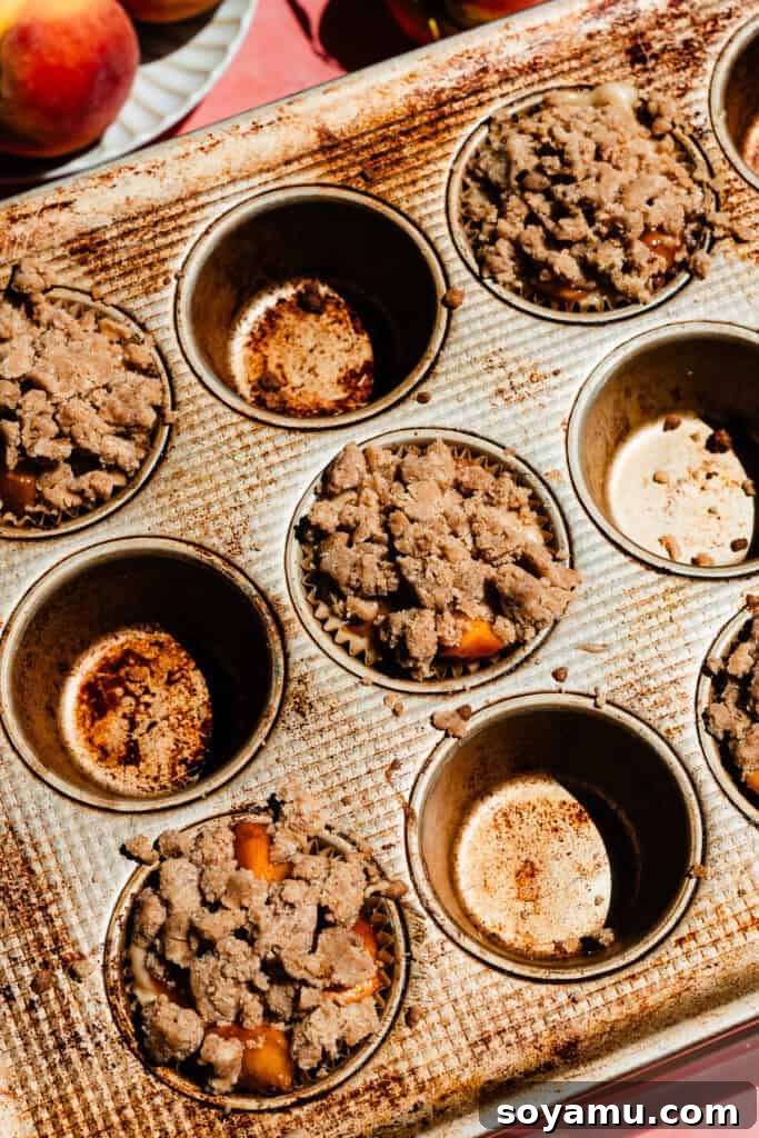 Southern-Style Peach Cobbler Muffins Recipe 12 Batter in the muffin tin, with streusel on top of the peaches and batter.