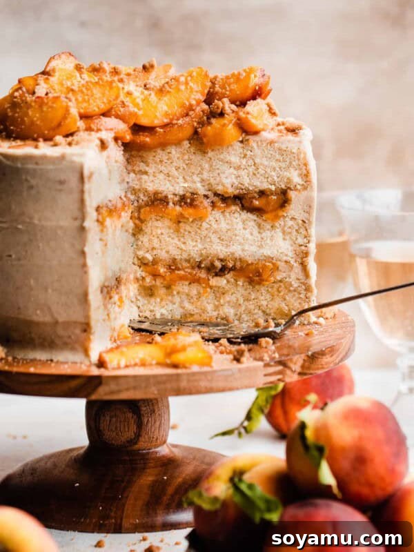 Southern-Style Peach Cobbler Muffins Recipe 18 A sliced peach cobbler cake on a cake stand with visible layers of brown butter frosting, peach filling, and streusel.