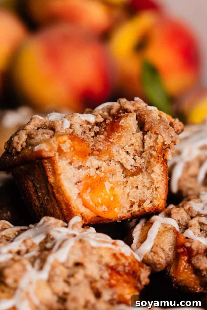 Southern-Style Peach Cobbler Muffins Recipe 3 A close-up of a peach cobbler muffin with a bite missing, showing the juicy peach pieces inside.