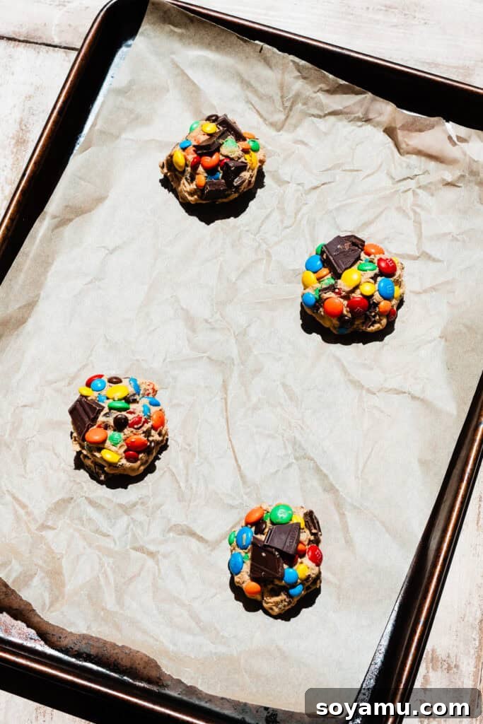 Thin, Chewy M&M Chocolate Chip Cookies 10 A bird's eye view of four cookie dough balls on a baking sheet.