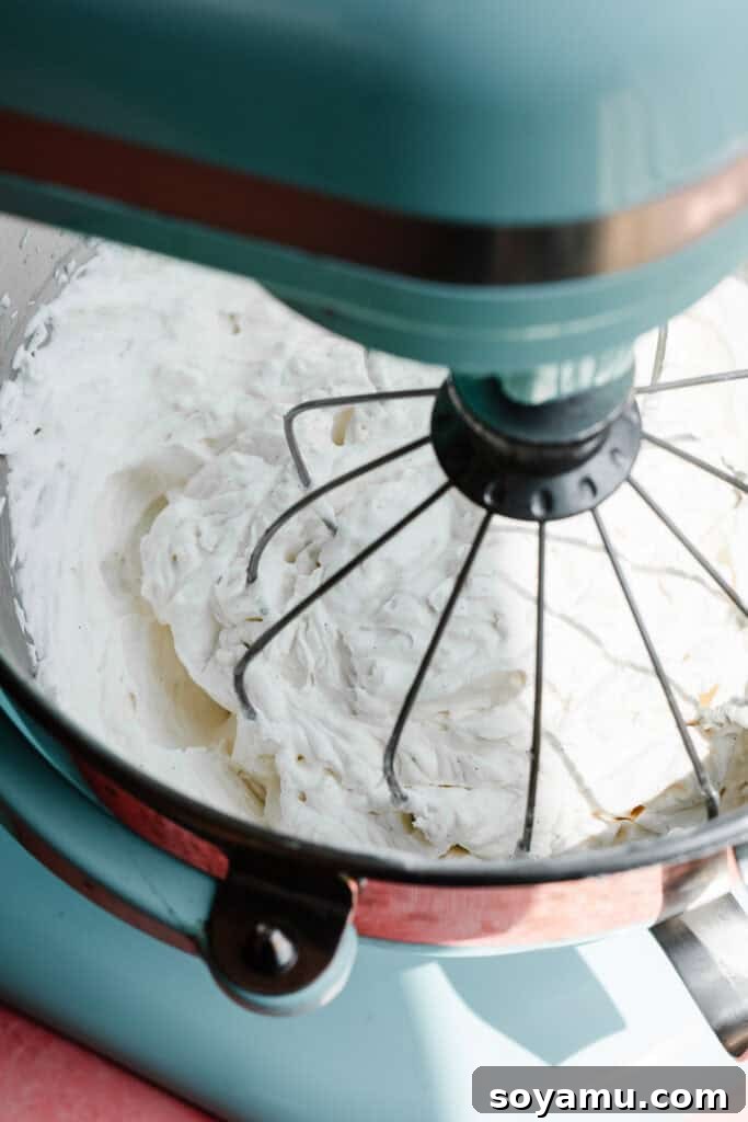 A stand mixer whipping cream with the whisk attachment.
