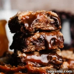 A close-up of a stack of three carmelitas, with caramel sauce dripping down the bars.