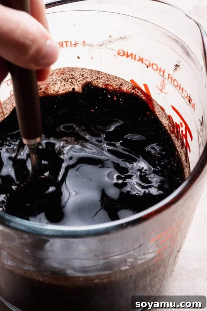 Decadent Moist Oreo Cake Recipe 5 A close-up of a whisk stirring together the water, cocoa, and espresso powder.
