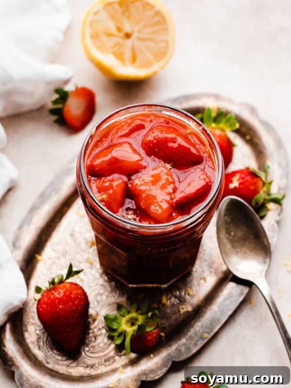 A jar of strawberry compote on a vintage metal tray.