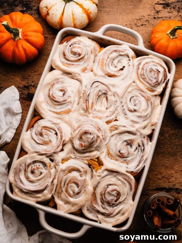 A pan of cream cheese frosted pumpkin cinnamon rolls.