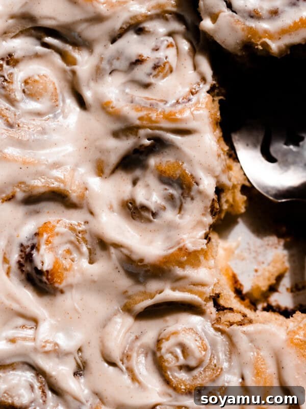 Cinnamon rolls in a pan frosted with cream cheese icing.