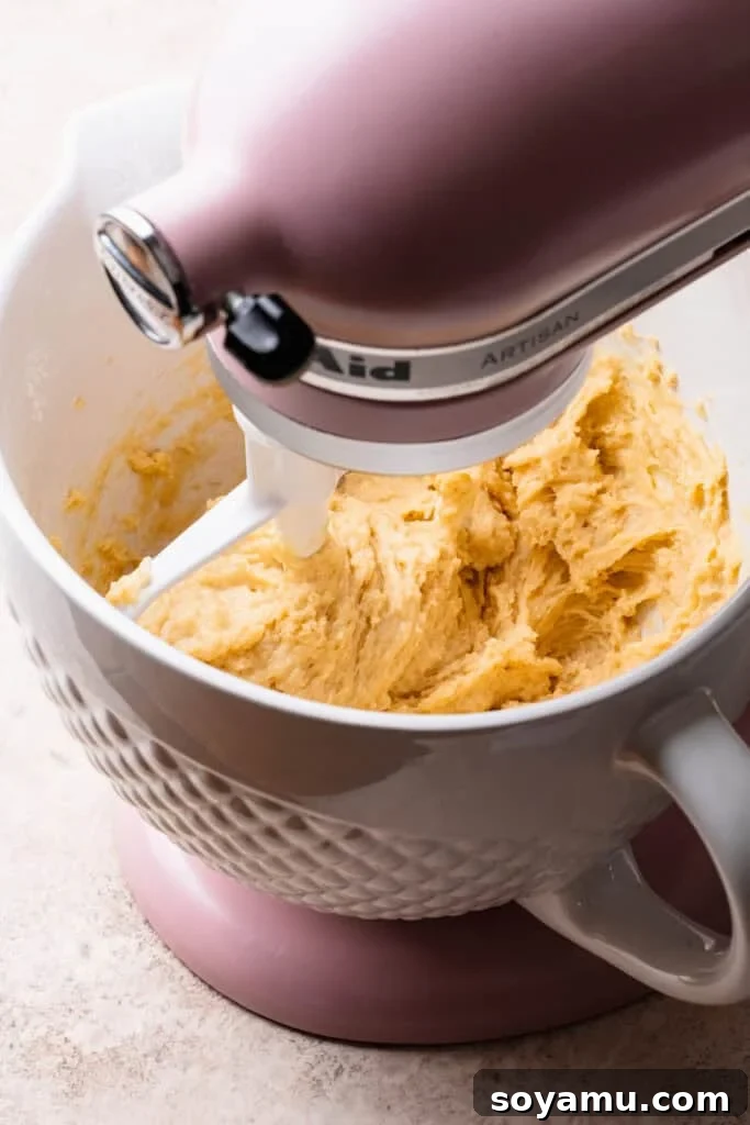 The dough mixture coming together with the paddle attachment, in the bowl of a stand mixer.
